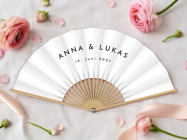 Personalisierter Hochzeitsfächer „Schlicht“ mit den Namen Anna & Lukas, ohne Motiv, nur in Großbuchstaben, Stoff in Weiß mit Druck in Schwarz, auf einem Hochzeitstisch